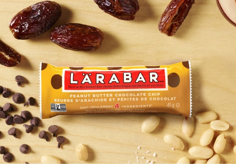 Larabar on wood surface with dates, peanuts and chocolate chips laid out next to it