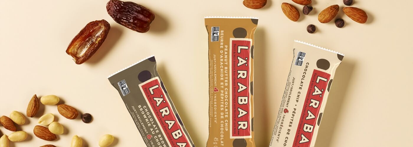 Three Larabars, surrounded by almonds, peanuts, dates and chocolate chips
